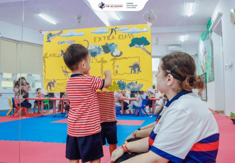 Hình ảnh bé học tiếng anh lớp 2 vui nhộn, đầy hứng khởi với sách và đồ chơi