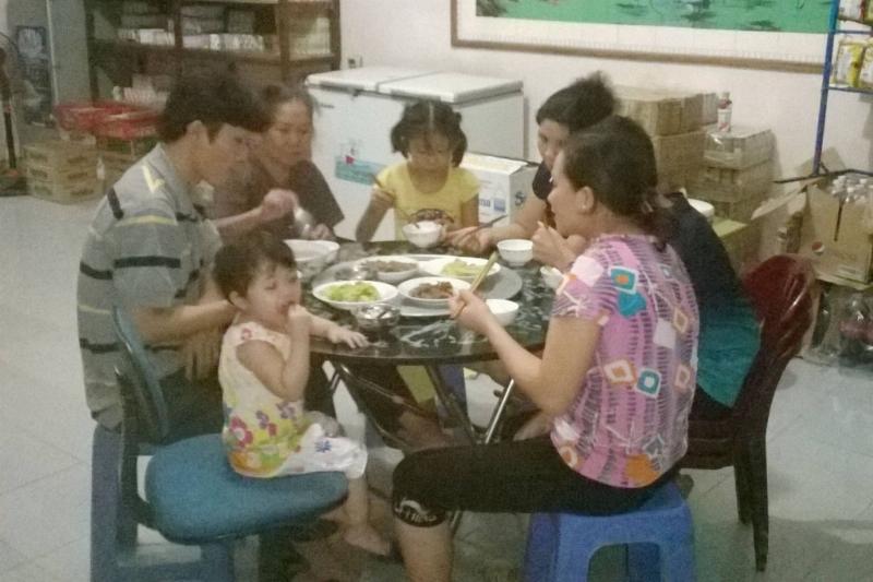 Một em bé đang ngồi ăn cơm cùng gia đình, thể hiện sự ngon miệng và ấm áp