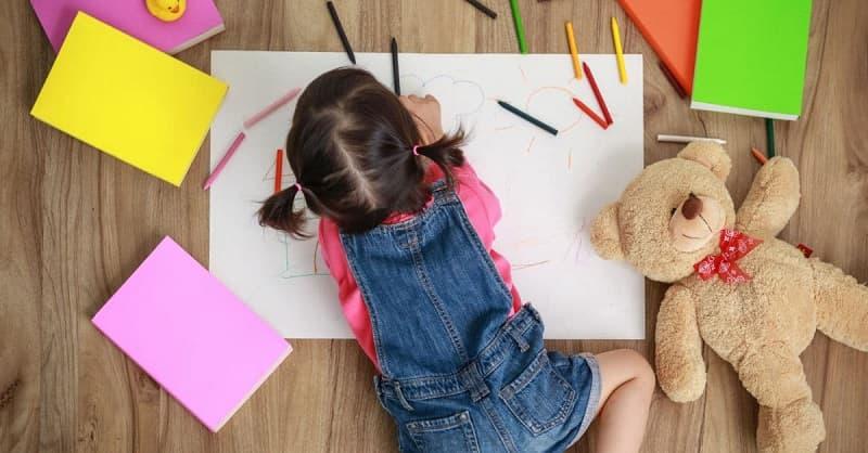 Bé gái ngồi tập trung tô màu nàng tiên cá, minh họa lợi ích phát triển kỹ năng vận động tinh và tập trung.