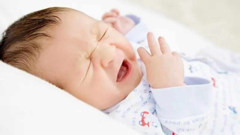 Mẹ nhẹ nhàng thoa dầu tràm cho trẻ sơ sinh bị ngạt mũi, thể hiện sự chăm sóc tận tâm, giúp bé dễ thở