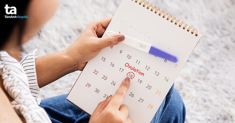 Người phụ nữ trẻ đang lắng nghe cơ thể để nhận biết có thai tại nhà không cần que thử, với ánh mắt suy tư và nhẹ nhàng chạm vào bụng mình