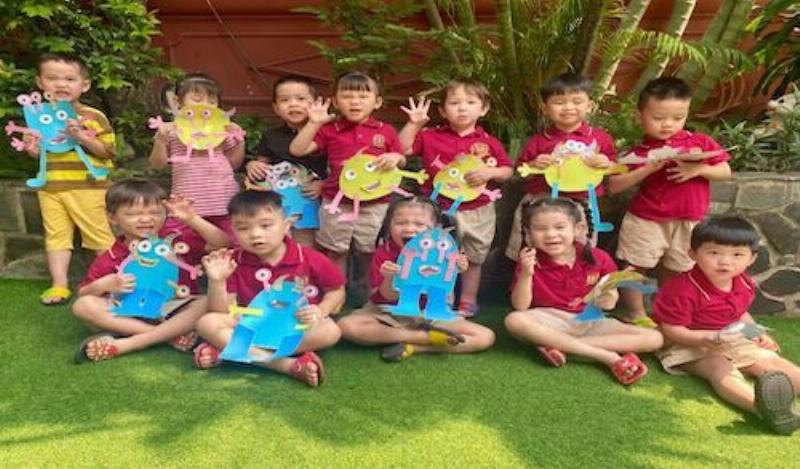 Gia đình (bố mẹ và con lớp 5) đang ngồi quây quần, thảo luận vui vẻ về một ý tưởng sáng tạo của con, thể hiện sự ủng hộ và đồng hành.