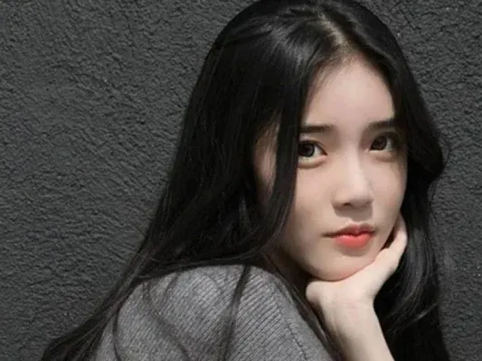 Cô gái với tóc dài uốn sóng nhẹ rẽ ngôi giữa, tôn nét mặt tròn béo